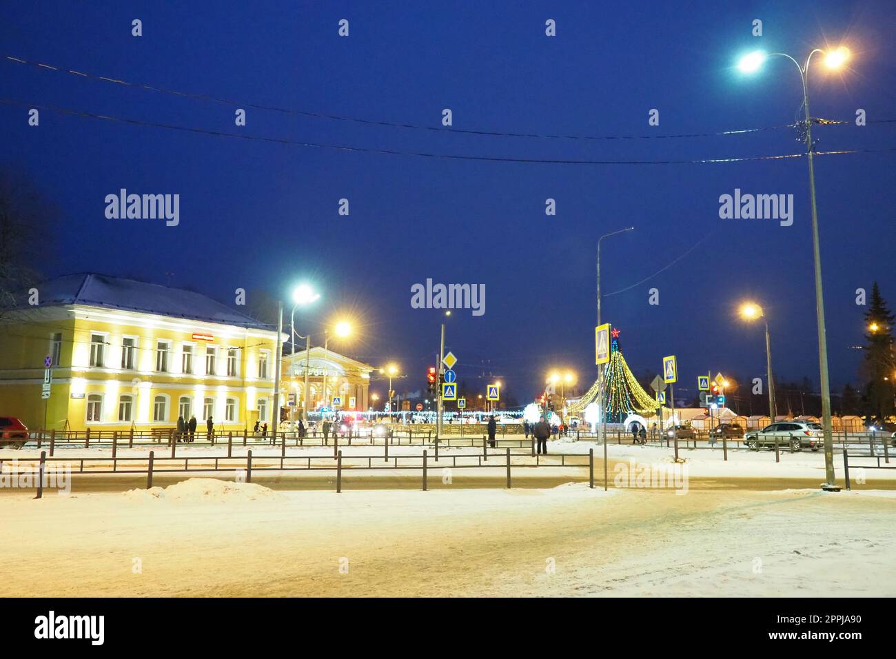 Petrozavodsk, Karelia, Russia, January 5 2023 New Year's city bustle. Garlands - Christmas trees and lighting fixtures. Cars drive along Kirov Square. People are walking in the snow. Karl Marx Avenue Stock Photo
