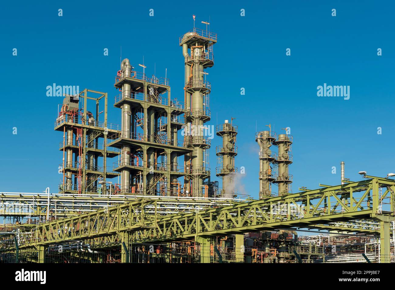 Green chimneys, tubes and metal grids against blue cloudless sky in chemical factory Stock Photo