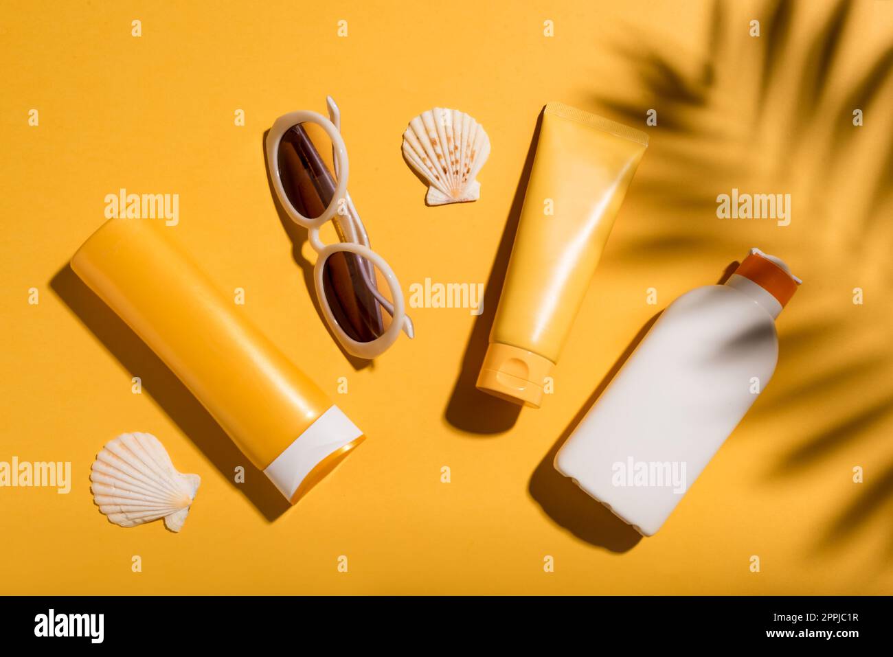 Sunblock lotion tubes and sunglasses on yellow background, top view. Summer vacation and skin care concept, sunscreen products, spf uv-protect cosmeti Stock Photo