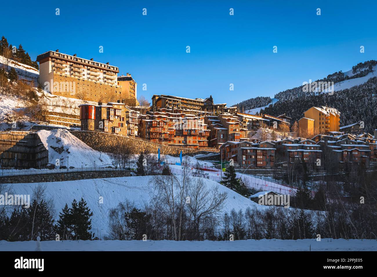 Sunset light illuminating Soldeu town ski slopes and snow capped mountains, Andorra Stock Photo