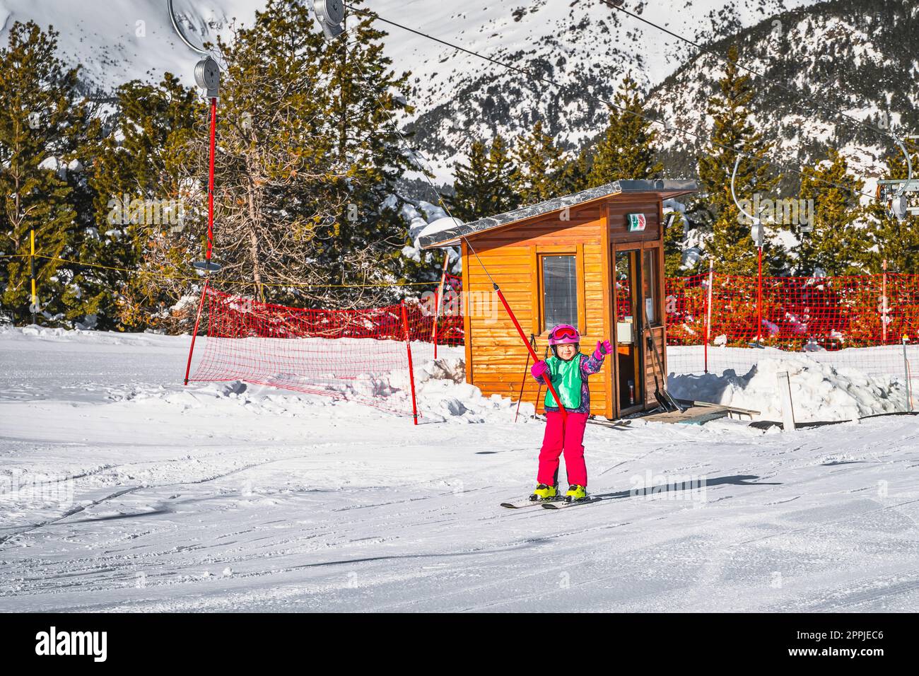 Young skier, a child, riding up on a ski drag lift and waving hand to a camera, Andorra Stock Photo