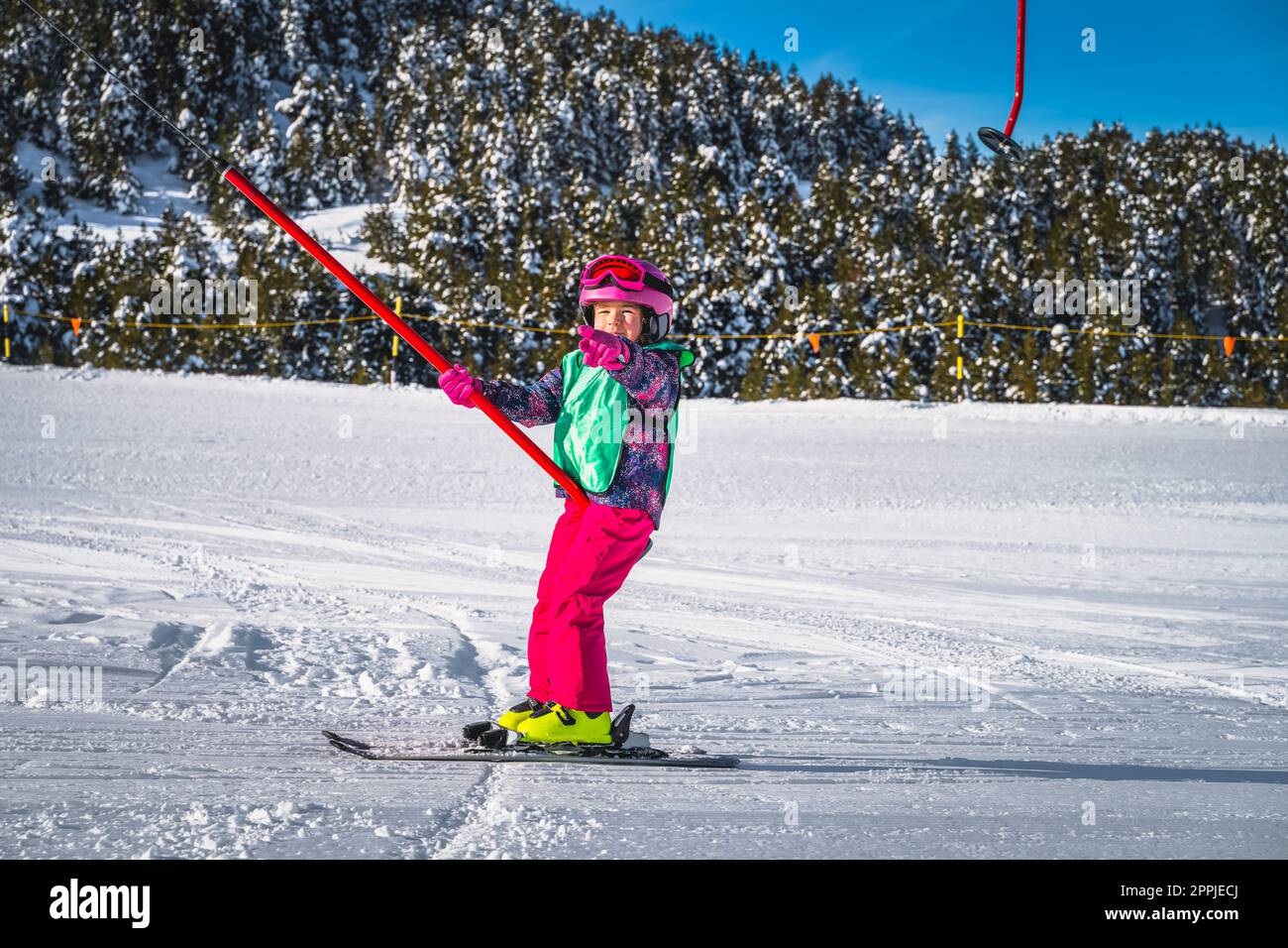 Young skier, a child, having fun when riding up on a ski drag lift, Andorra Stock Photo
