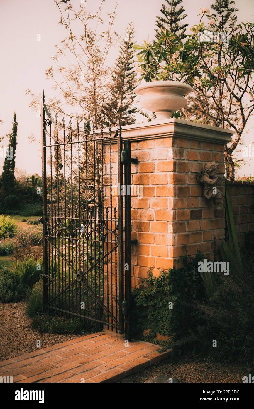 old garden cast iron steel gate on Stone column  arch entrance wall Stock Photo