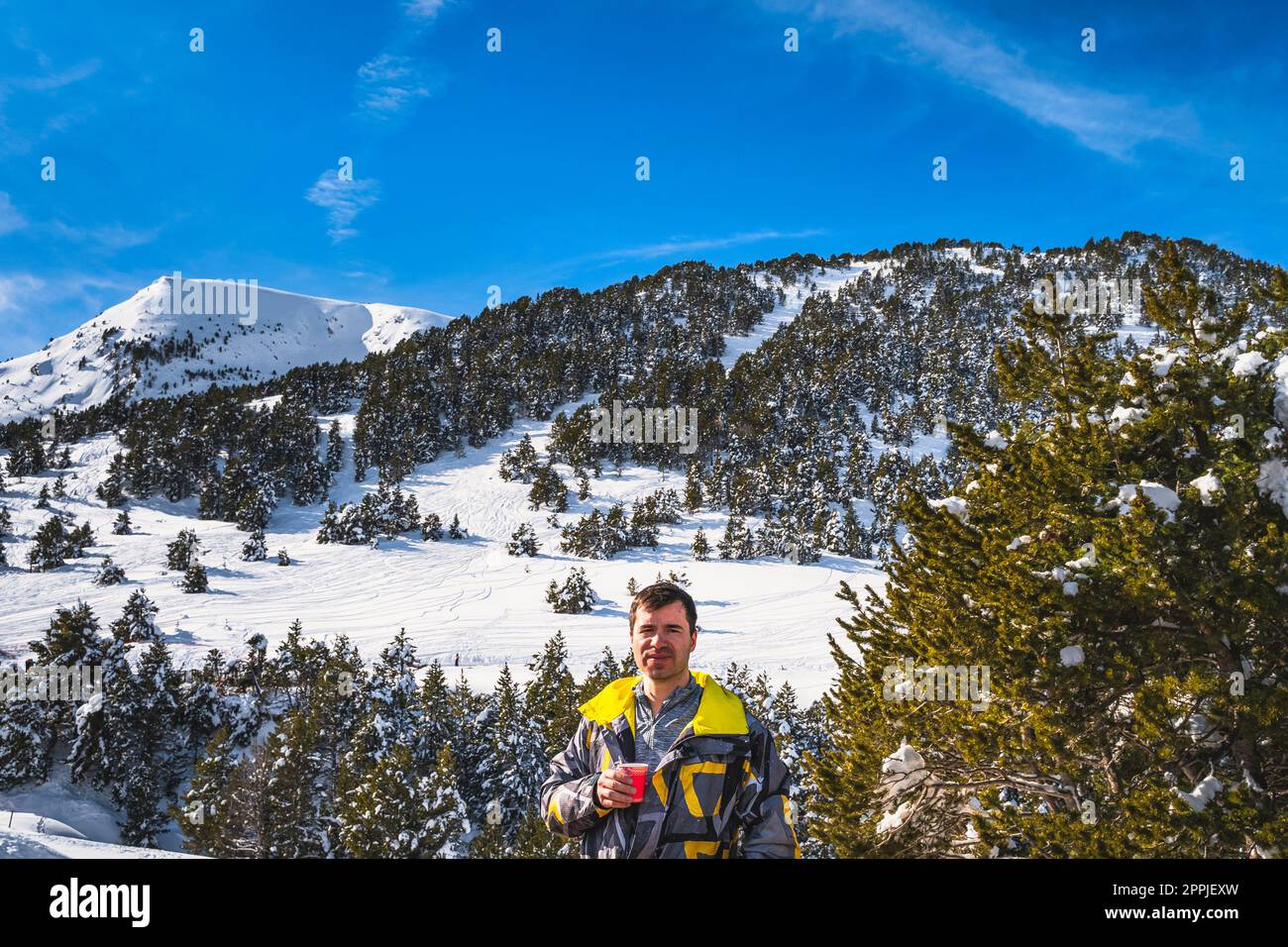 Men drinking coffee or tee with snowy forest and mountains in background, Andorra Stock Photo