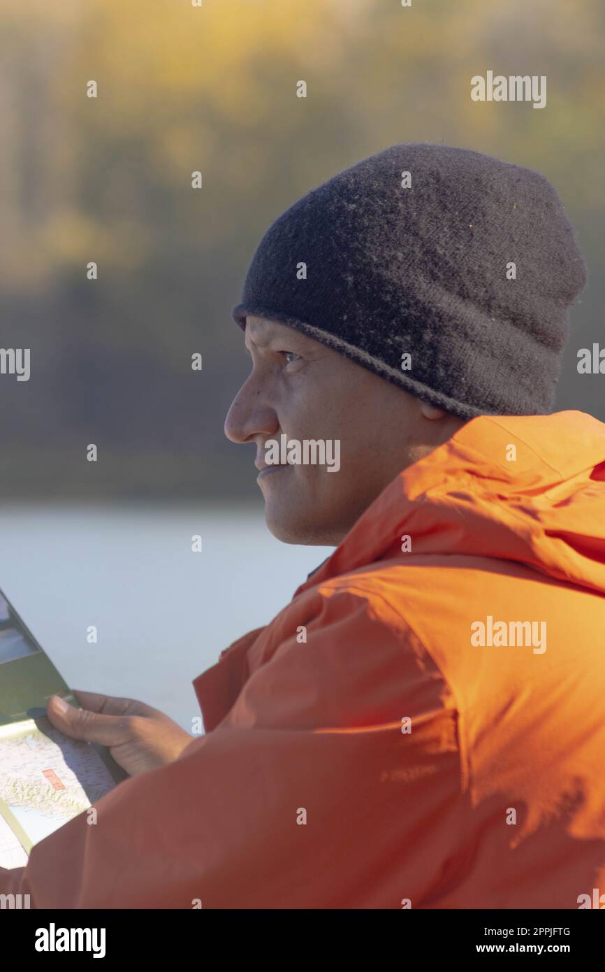 Portrait of traveler man at lake in autumn with a map Stock Photo