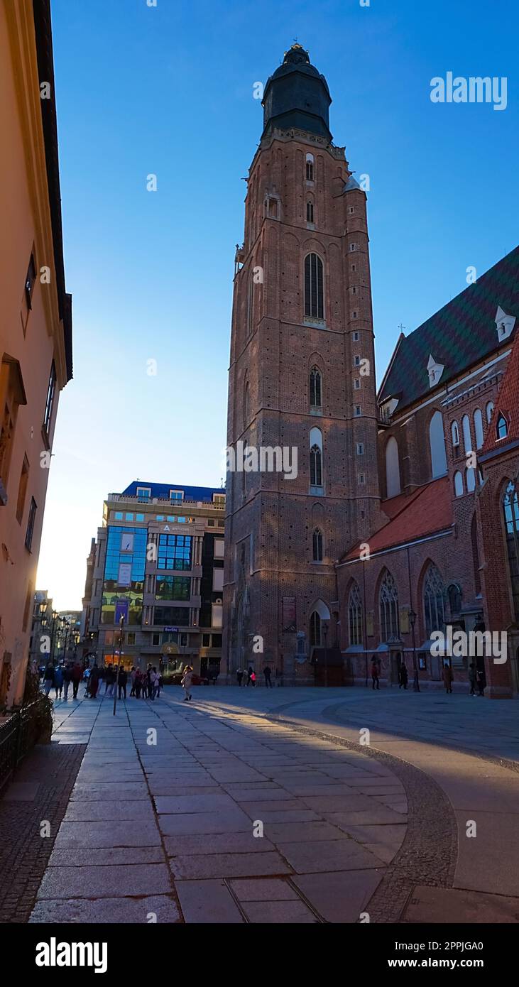 The St Elizabeth Church is hidden behind the houses of old Odrzanska street located next to the Market Square on August 18 in Wroclaw. Stock Photo