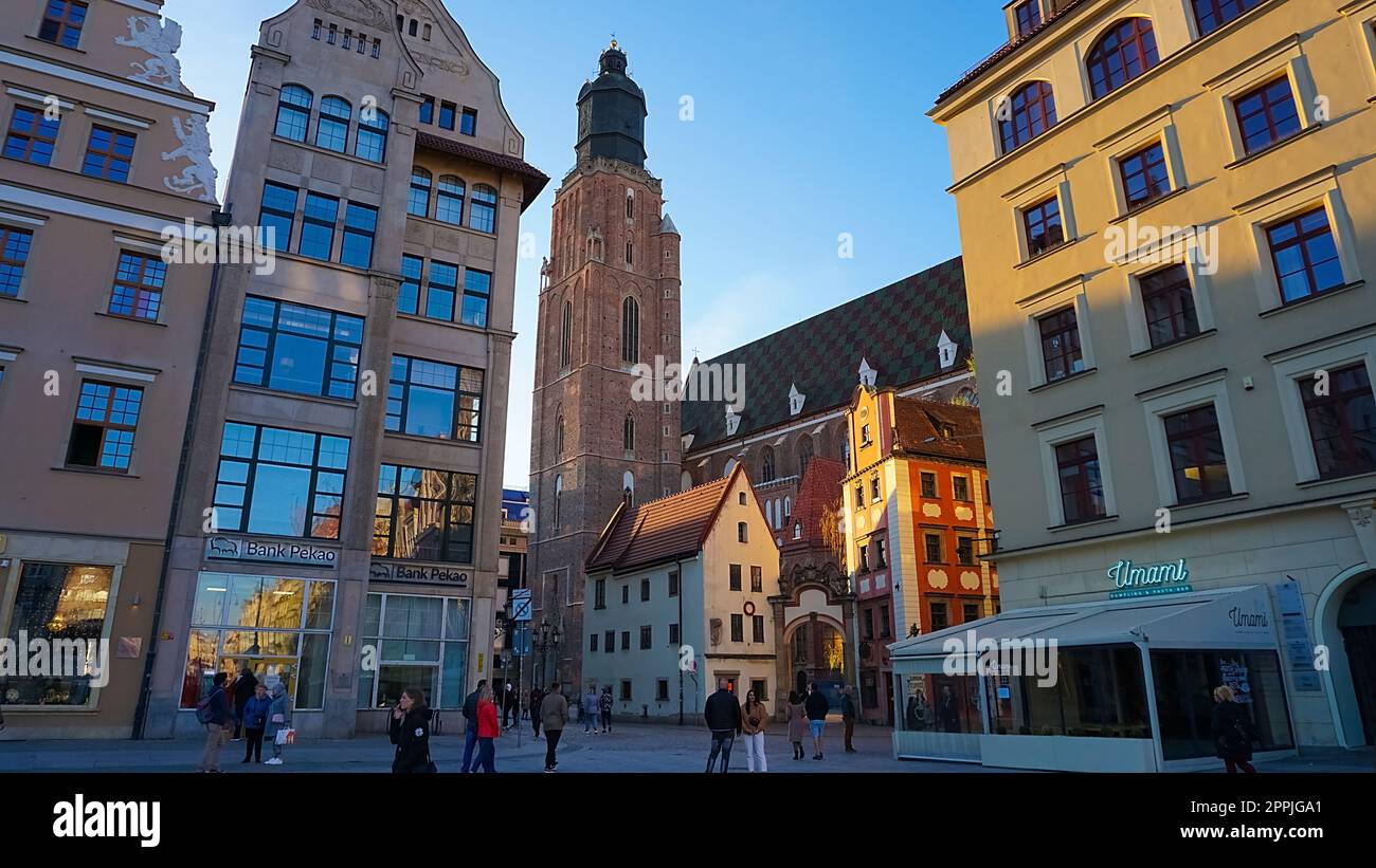 The St Elizabeth Church is hidden behind the houses of old Odrzanska street located next to the Market Square on August 18 in Wroclaw. Stock Photo