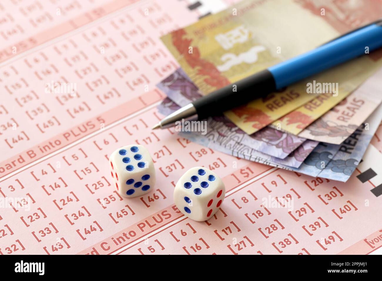 Dice cubes with Brazilian money bills on blank of lottery game. Concept of luck and gambling in Brazil Stock Photo