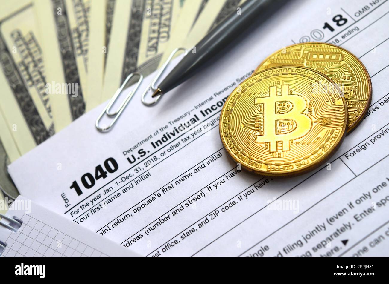 The pen, bitcoins and dollar bills is lies on the tax form 1040 U.S. Individual Income Tax Return. The time to pay taxes Stock Photo