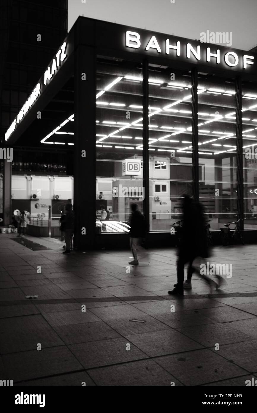Vertical shot of the entrance to Potsdamer Platz train station with people walking by at night Stock Photo