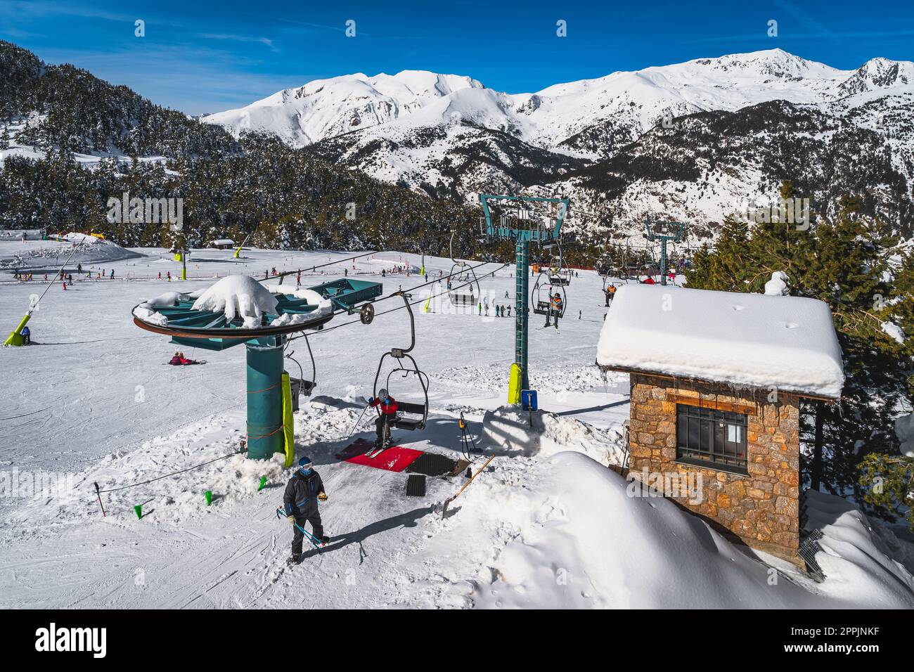 People taking off from chair ski lift with snowy mountains in a background, Andorra Stock Photo