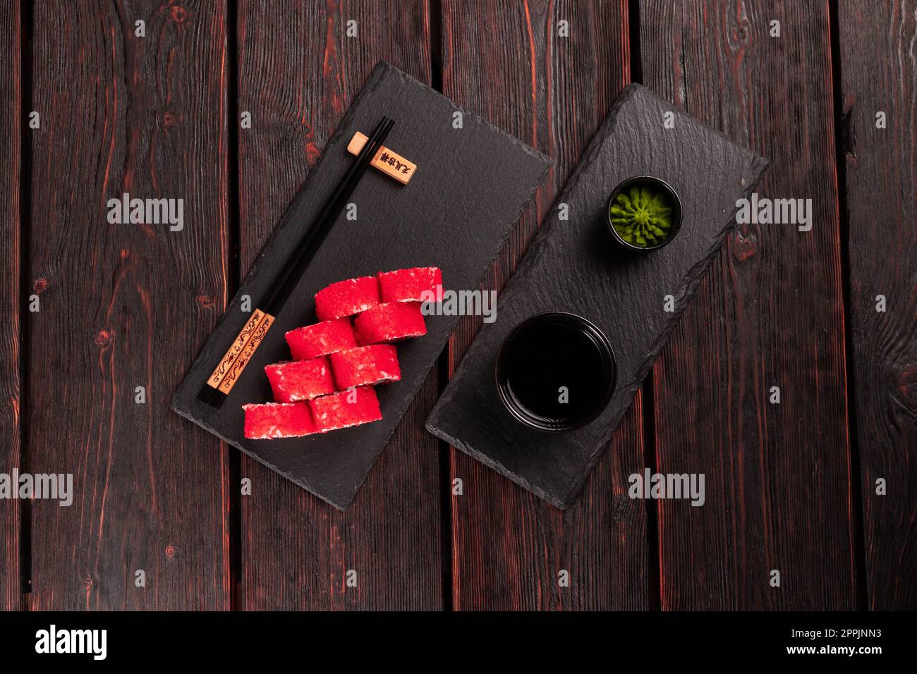 California sushi roll with salmon, avocado cucumber and tobiko caviar served on black board top view - Japanese food Stock Photo