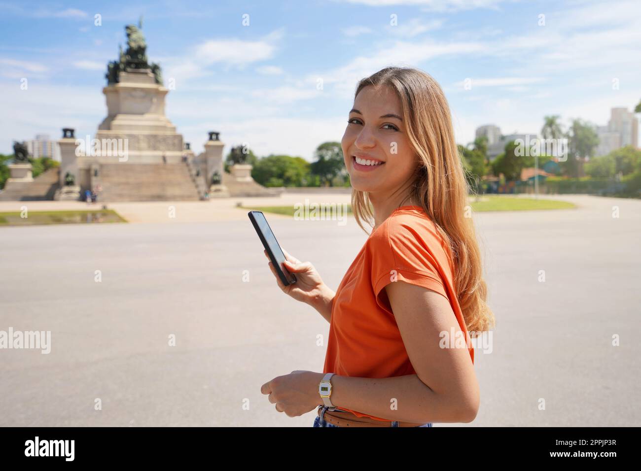 Confident young business woman holding her mobile phone smiling at camera Stock Photo