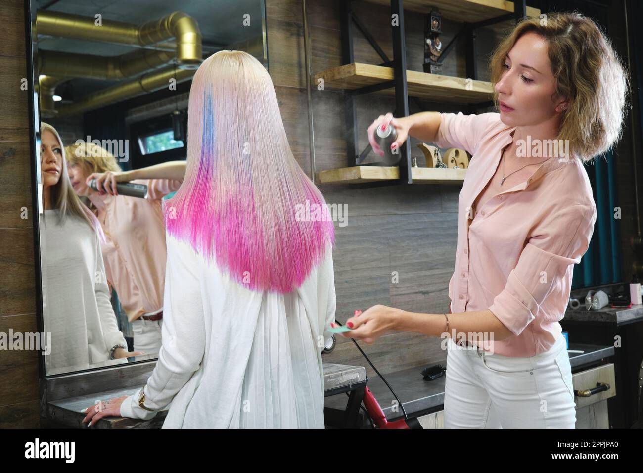 Beautiful blond girl with colored pink hair in a hairdressing salon. Stock Photo
