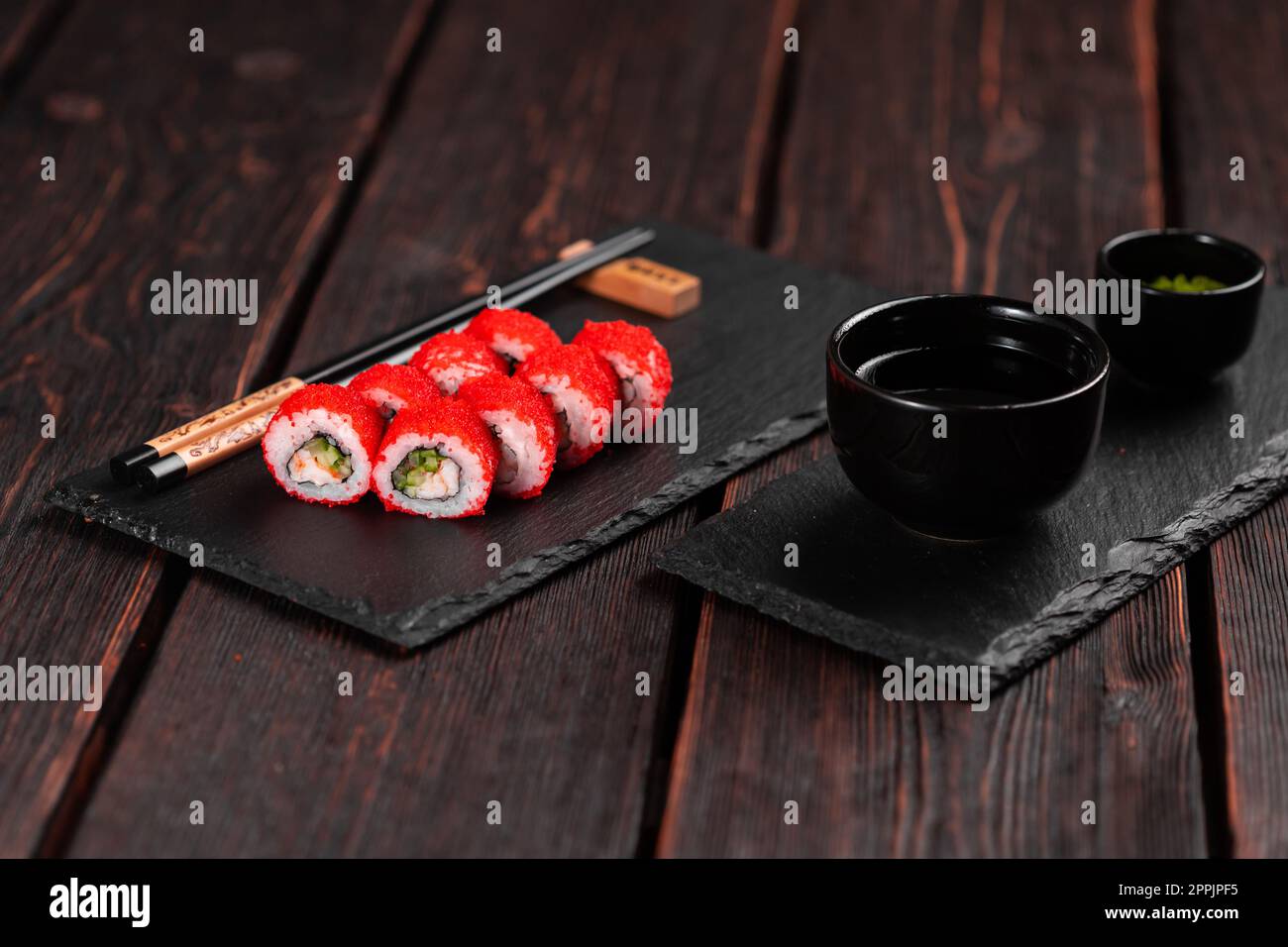 Sushi roll with shrimp and cucumber and tobiko caviar served on black board close-up - Japanese food Stock Photo