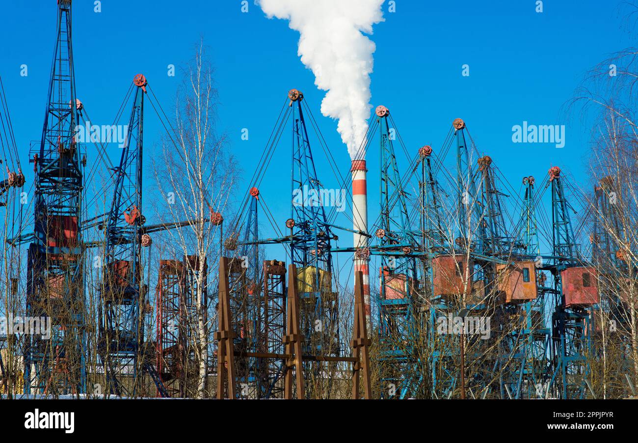Industrial landscape, cranes, pipes with smoke. Air pollution from smokestacks, ecological problems. Stock Photo