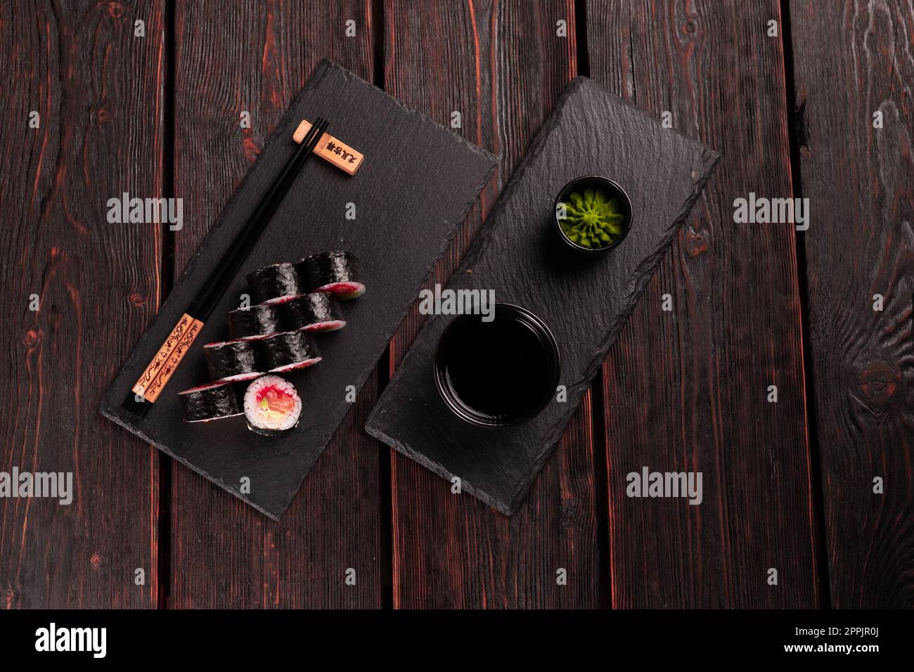 Maki sushi roll with salmon avocado and tobiko caviar served on black board top view - Japanese food Stock Photo