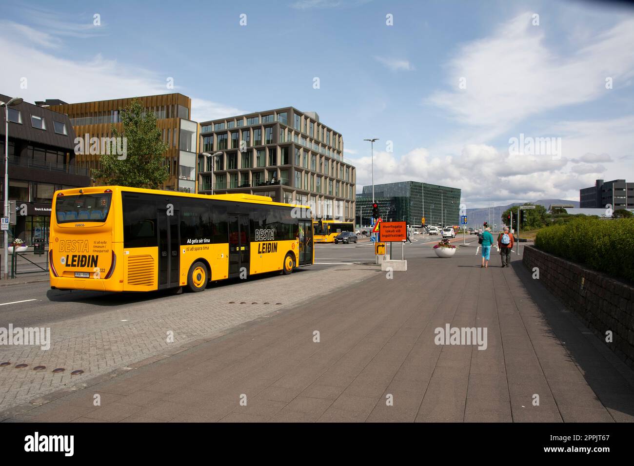 view on the Laekjargata, Harpa museum in background, yellow Besta Leidin public transport bus in foreground Stock Photo