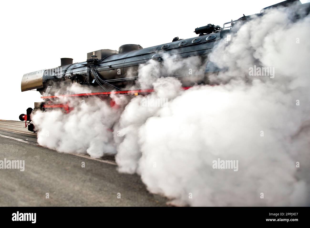 A steam locomotive spews smoke and steam at full speed Stock Photo
