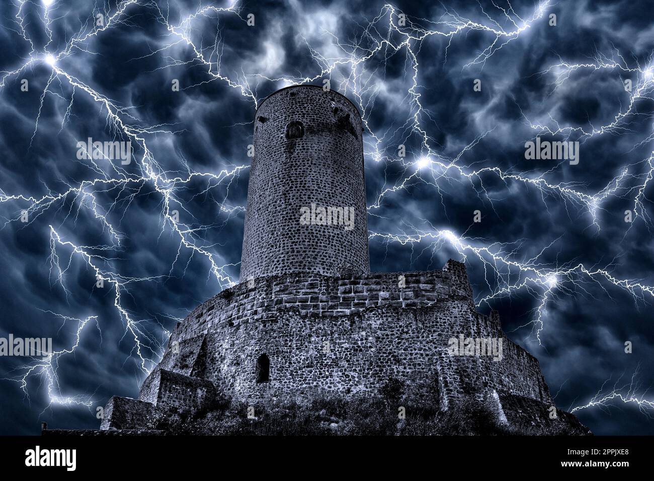 Ominous night sky with thunderstorms and lightning behind the dark facade of an old knight's castle Stock Photo