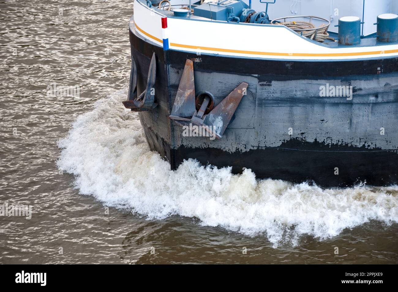 Detail of bow wave and bow with thinned anchors of a barge in full sail on a river Stock Photo