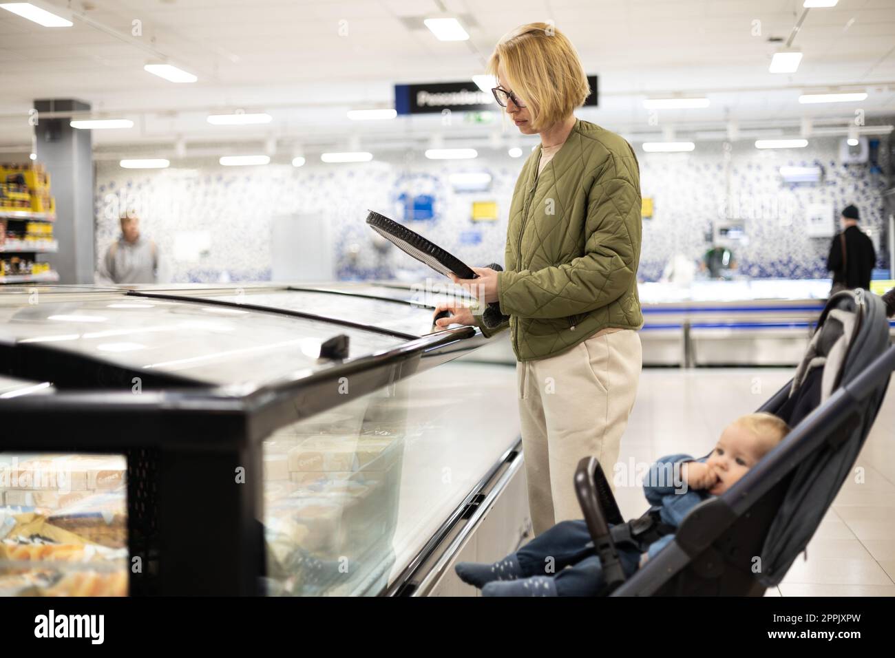 Casualy dressed mother choosing frozen products in department of