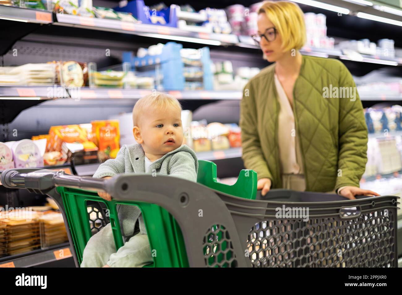 Casualy dressed mother choosing canned products in department of ...