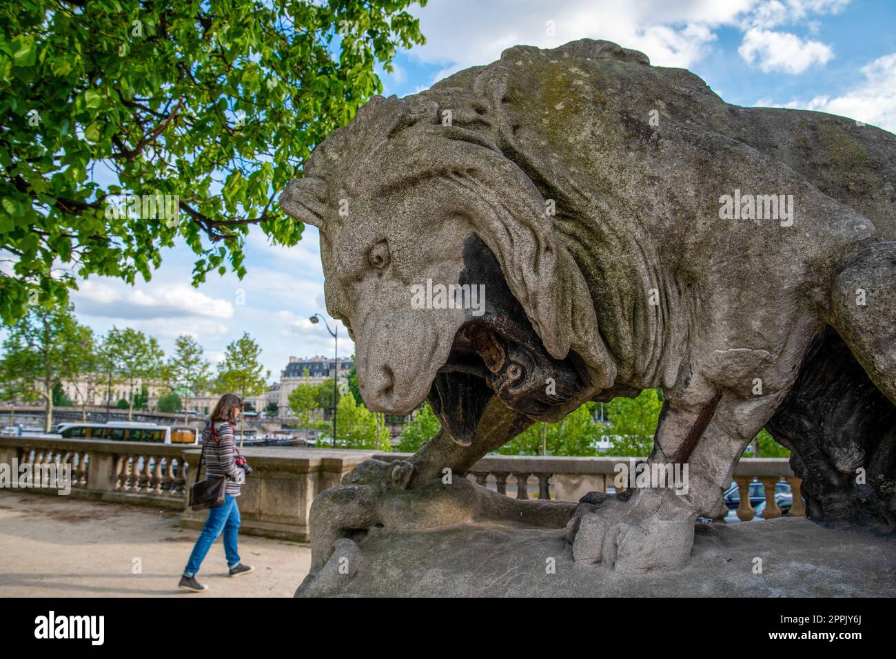 Giant lion sculpture roaring at a Person walking by, Park of Louvre Palace in Paris Stock Photo