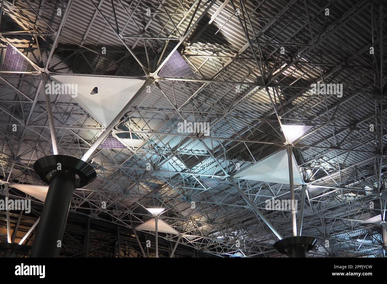 Metal structures under the ceiling. Decorative details of the airport ceiling . Concrete beams, glass windows and metal elements as public building interior design. Abstract avant-garde architecture. Stock Photo