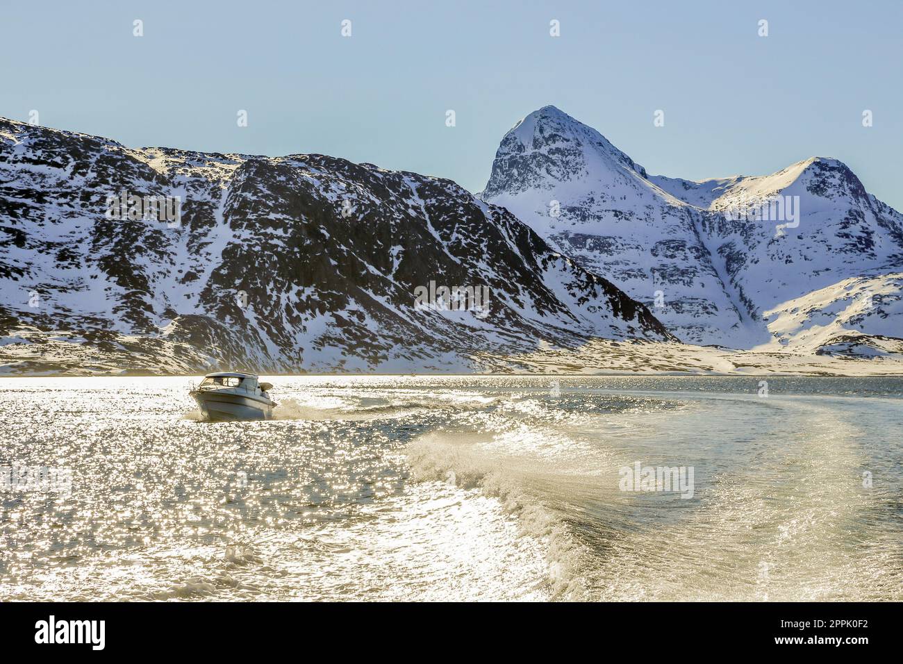Motor boat in the middle of Nuuk fjord with frozen rocks in the ...