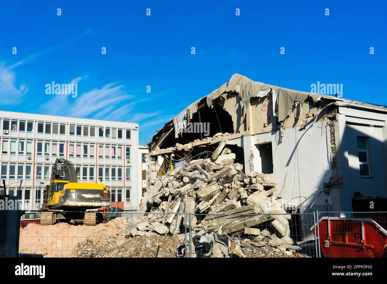 Demolition of the old building with sloopkraan against blue clouds sky ...