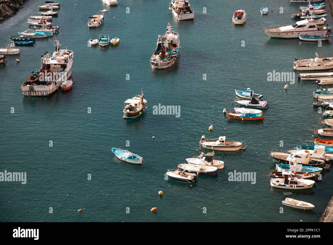 Small fishing boats in turquoise, clear water, Procida, Italy. Stock Photo