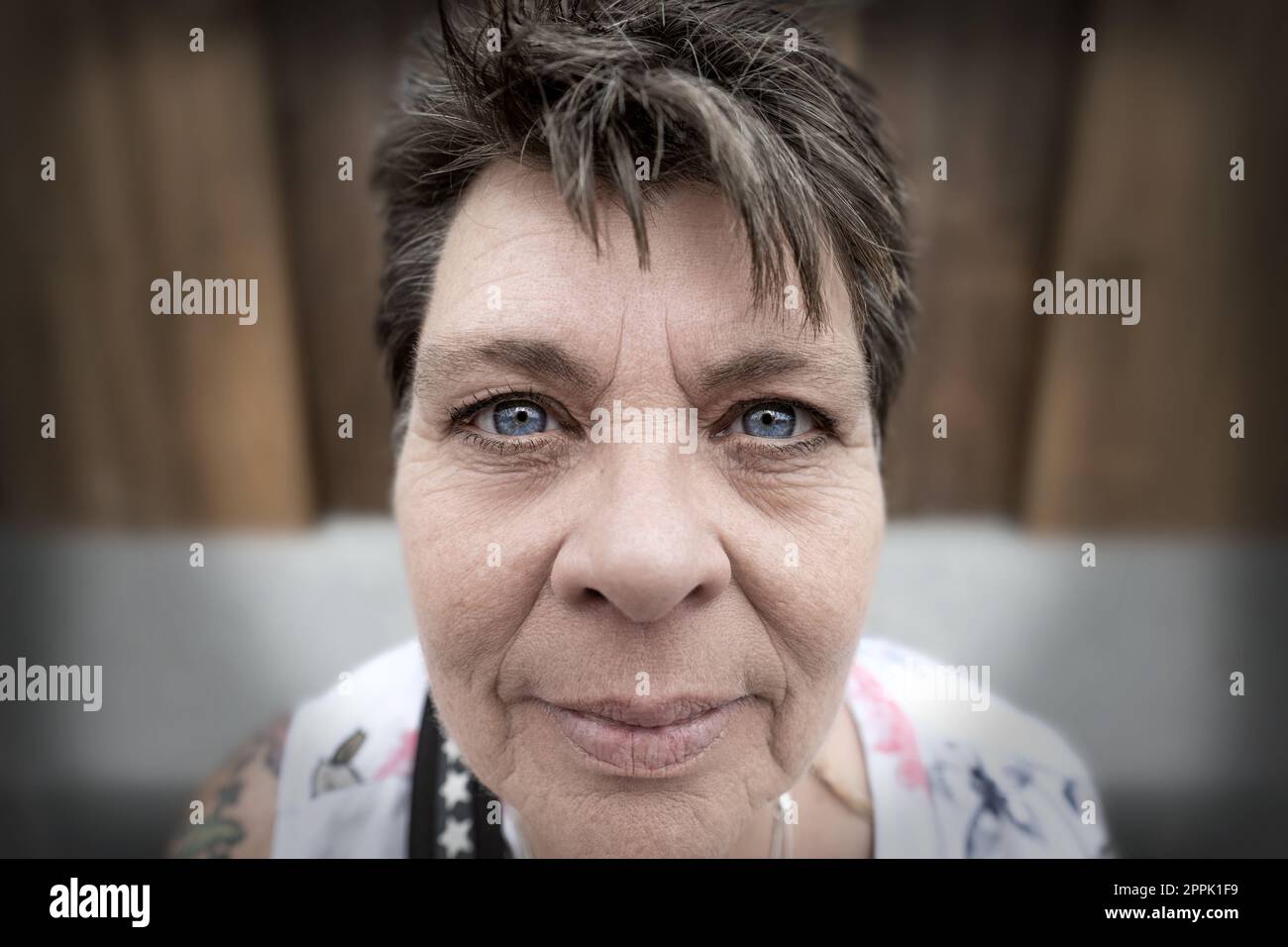 Mature lady, smiling, close-up, steel blue eyes, looking into camera. Stock Photo