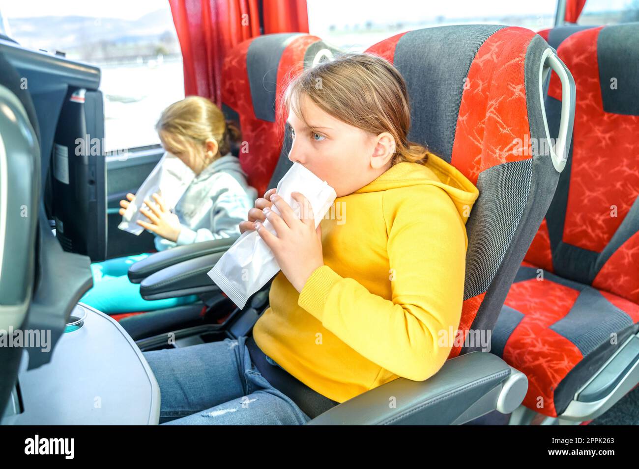 Girl is sick, vomits in bag. Bus road traveling. Girl kid feels bad, rides on large comfortable