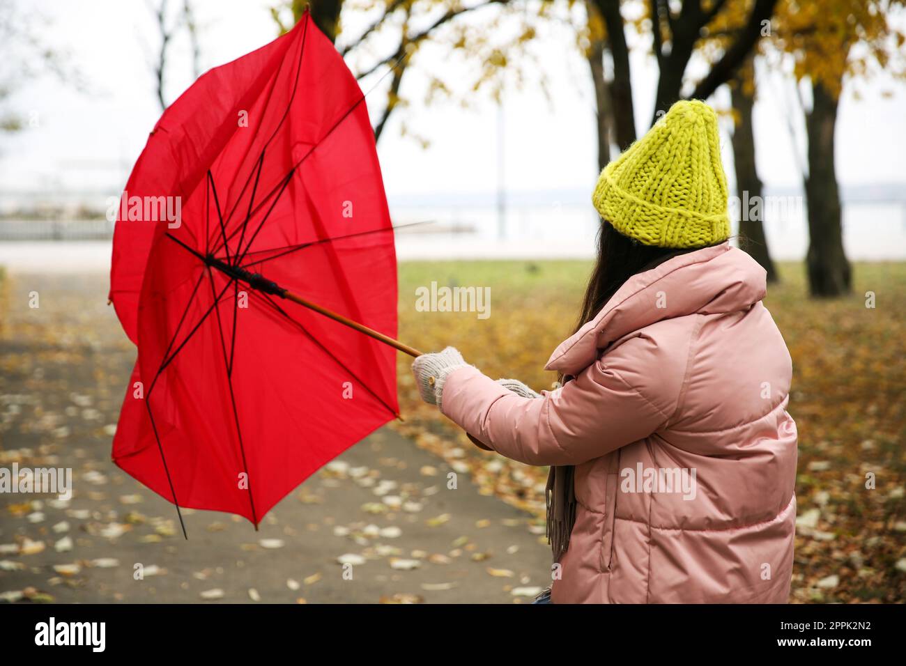 Woman with red umbrella caught in gust of wind outdoors Stock Photo