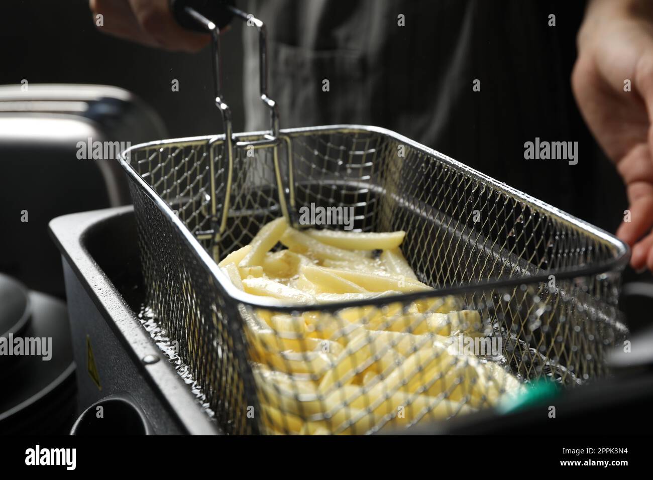 Chef cooking delicious french fries in hot oil, closeup Stock Photo