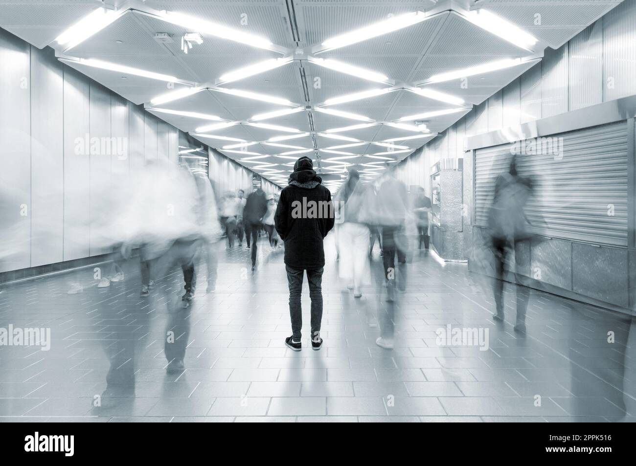 Long exposure picture with lonely man shot from behind at busy walkway ...
