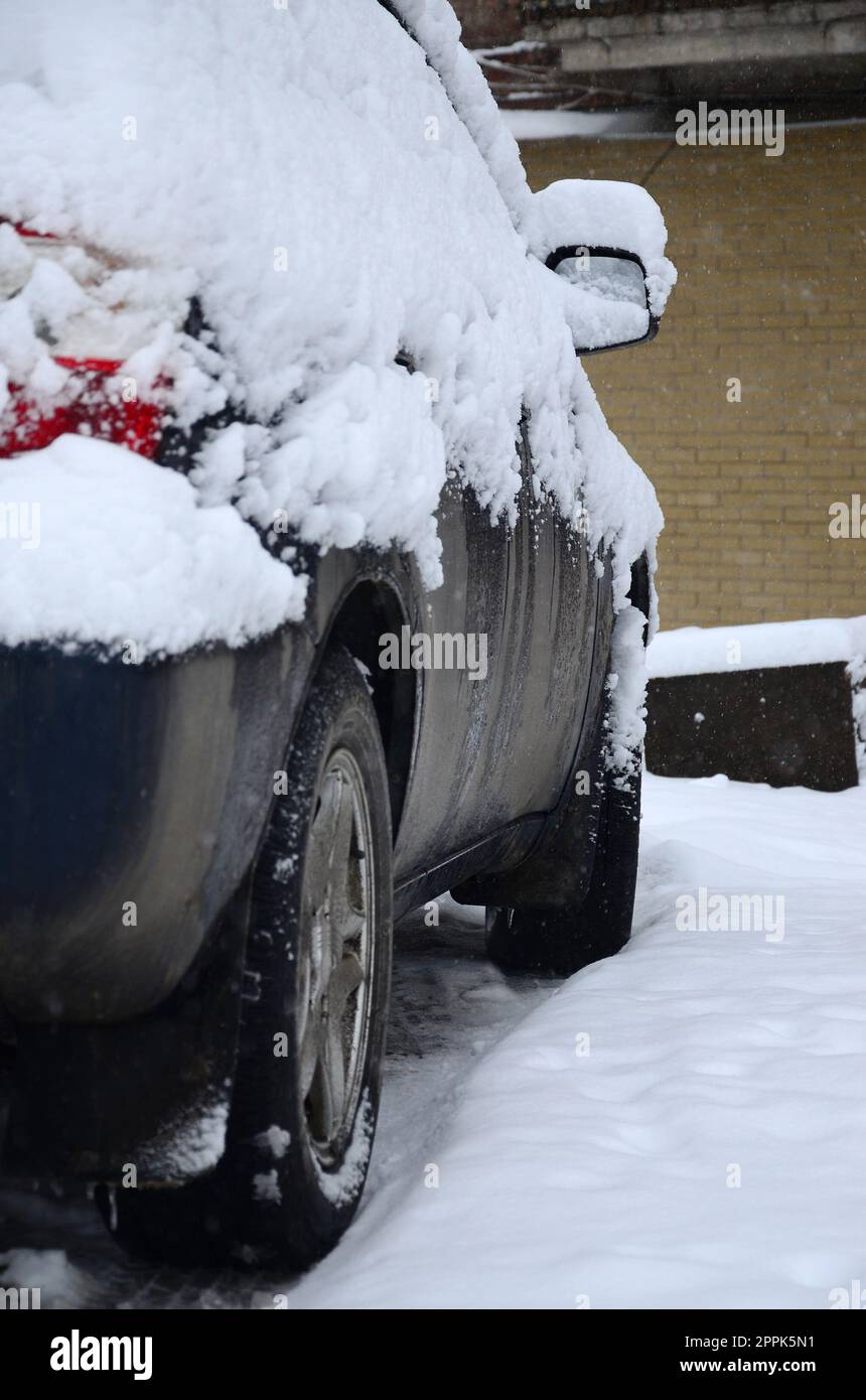 Fragment of the car under a layer of snow after a heavy snowfall. The body of the car is covered with white snow Stock Photo