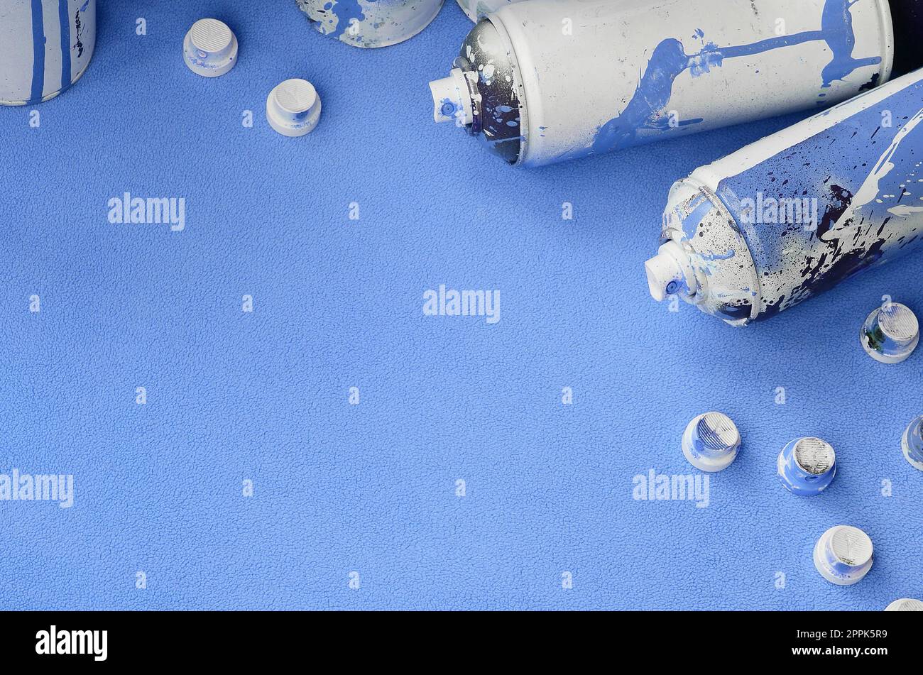 Some used blue aerosol spray cans and nozzles with paint drips lies on ...