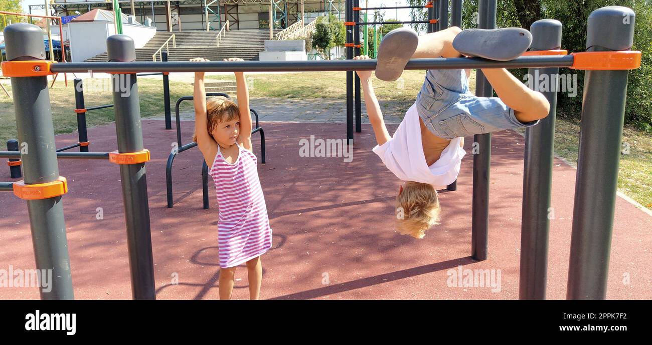 Sremska Mitrovica, Serbia, September 13, 2020. A boy and a girl on the sports or playground are engaged in physical exercise. Child in a white t-shirt. Girl in a striped dress laughs. Stock Photo