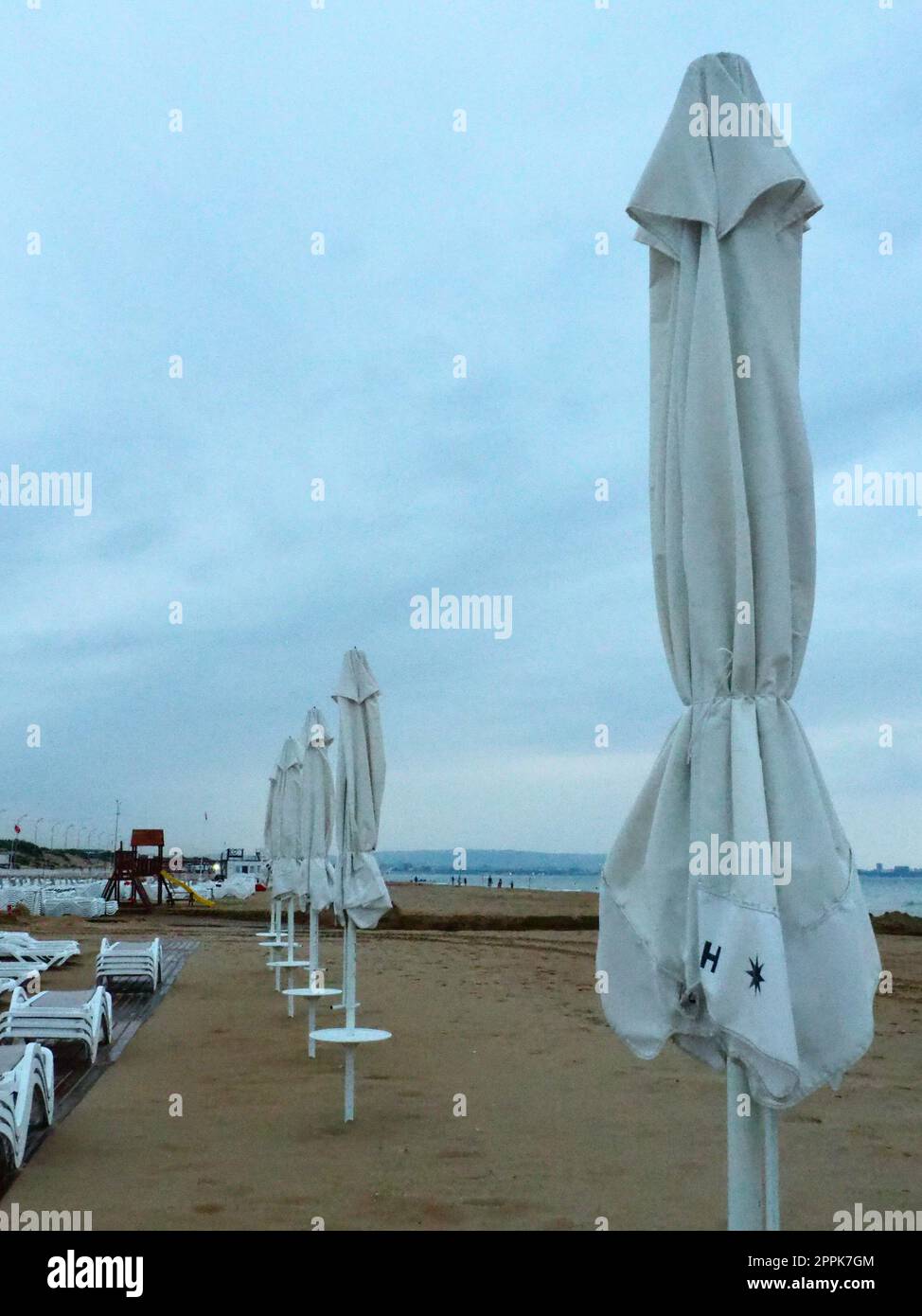 Wet sunbeds and umbrellas on the sea beach during heavy rain storm