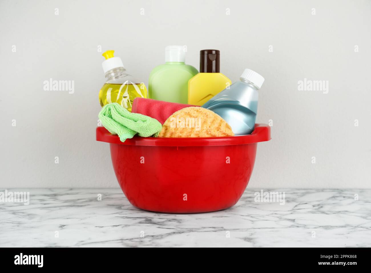 Red basin with cleaning products on marble table Stock Photo