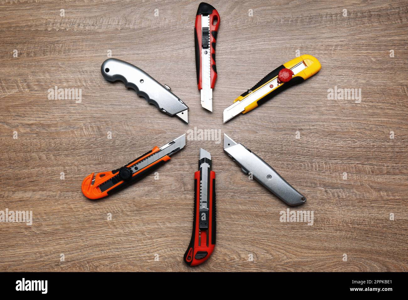 Many different utility knives on wooden table, flat lay Stock Photo