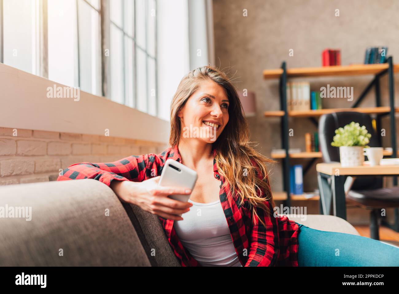 Woman relax at home in her free time with mobile phone Stock Photo
