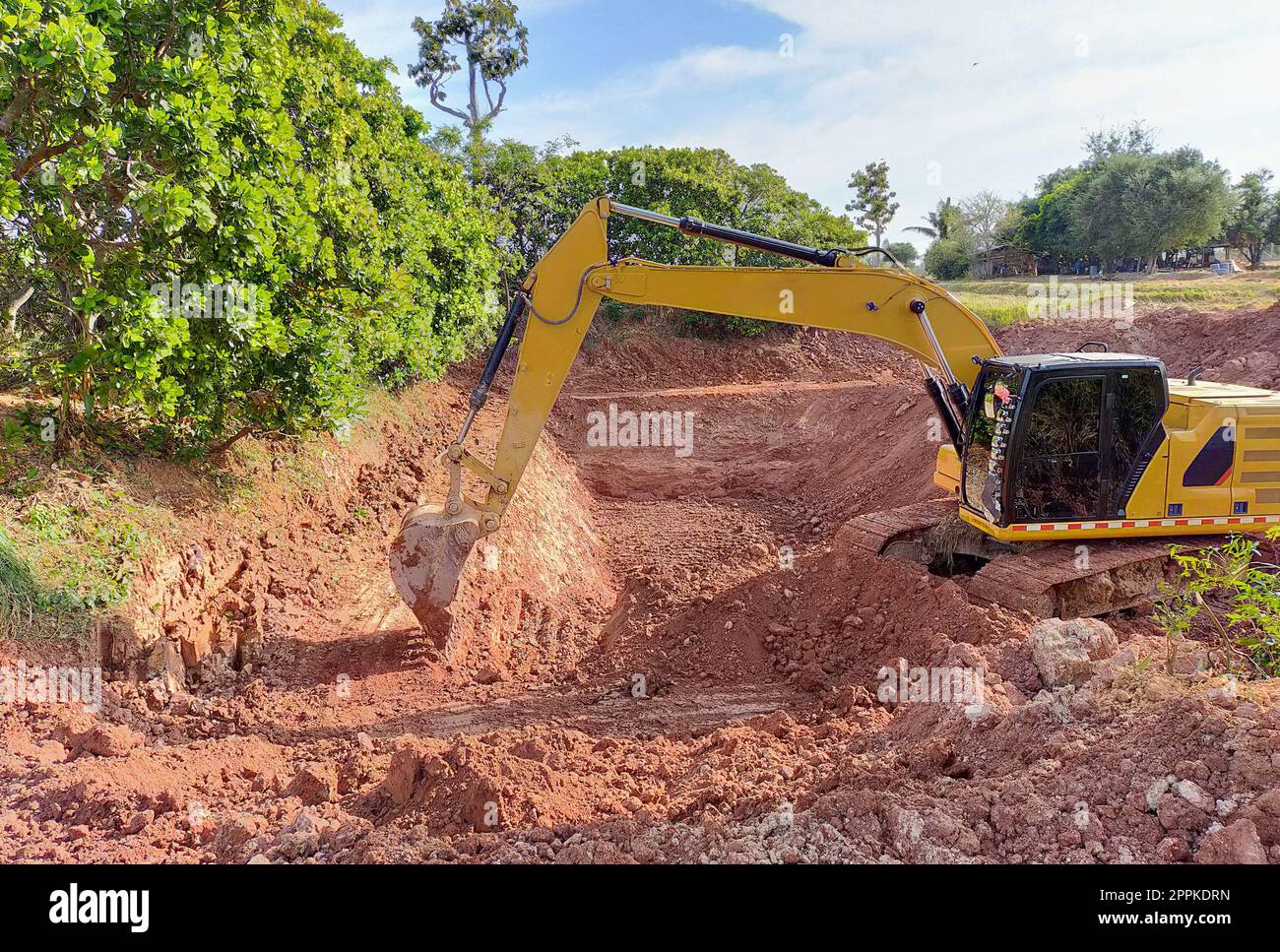 Backhoe bucket digging the soil at agriculture farm to make pond. Crawler excavator digging at shale layer. Excavating machine. Earth moving equipment. Excavation vehicle. Construction business. Stock Photo