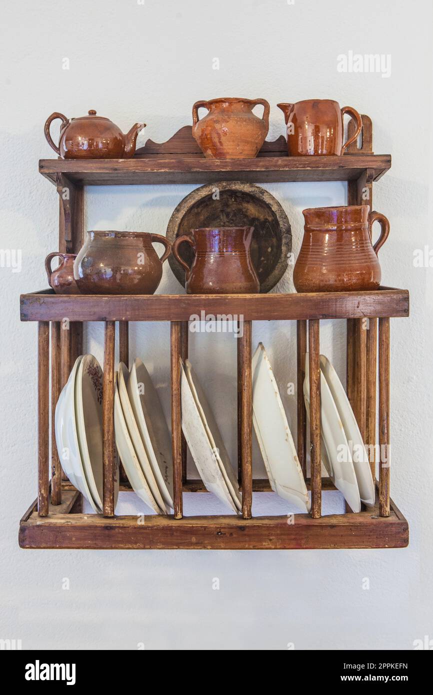 Old wooden plate rack full of pottery. Cottage kitchen concept Stock