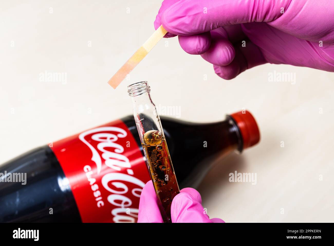 pink litmus paper shows acidity of Coca-Cola Stock Photo