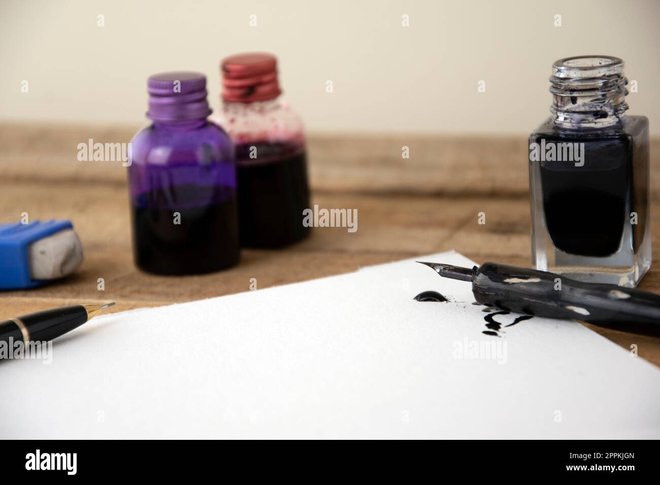 Ink and artists pen with white art paper, ink spill, wooden background Stock Photo