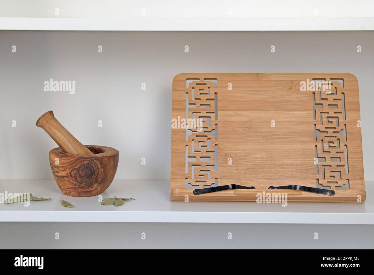 White shelf with wooden recipe book stand and mortar and pestle Stock Photo