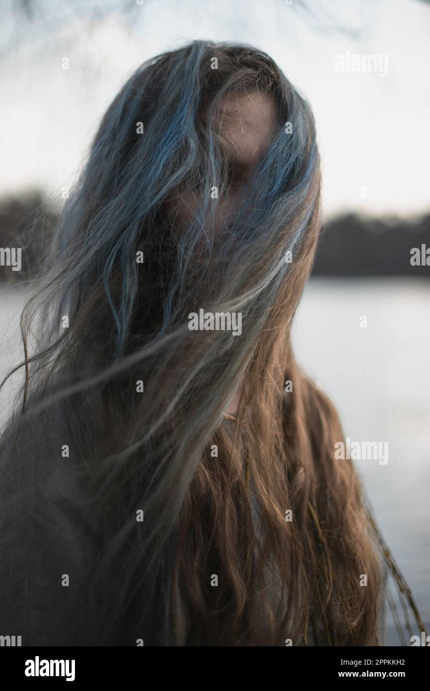 Close up long gray brown hair hiding woman face with wind portrait picture Stock Photo